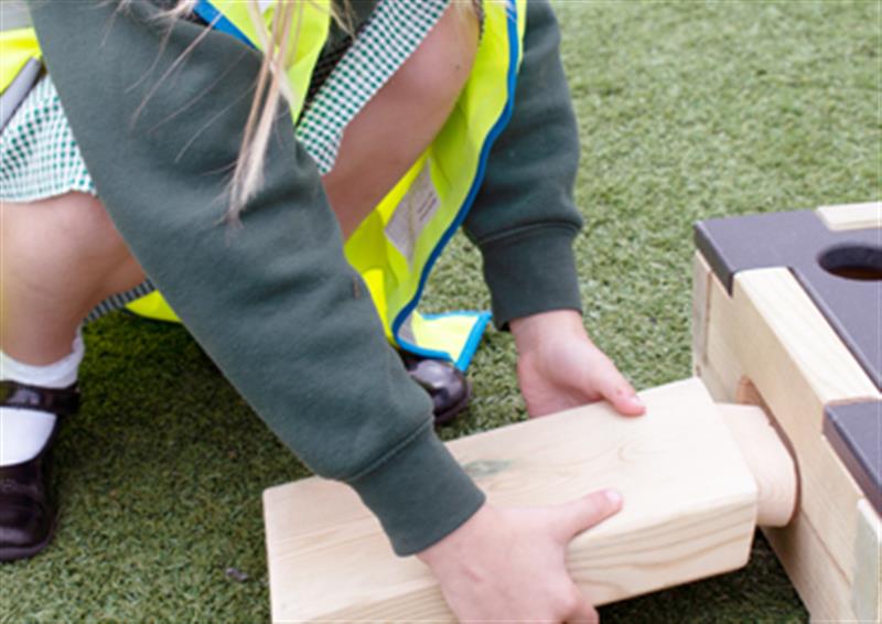 Close up image of a child trying to slot an Entry Plank into a Play Builder Block